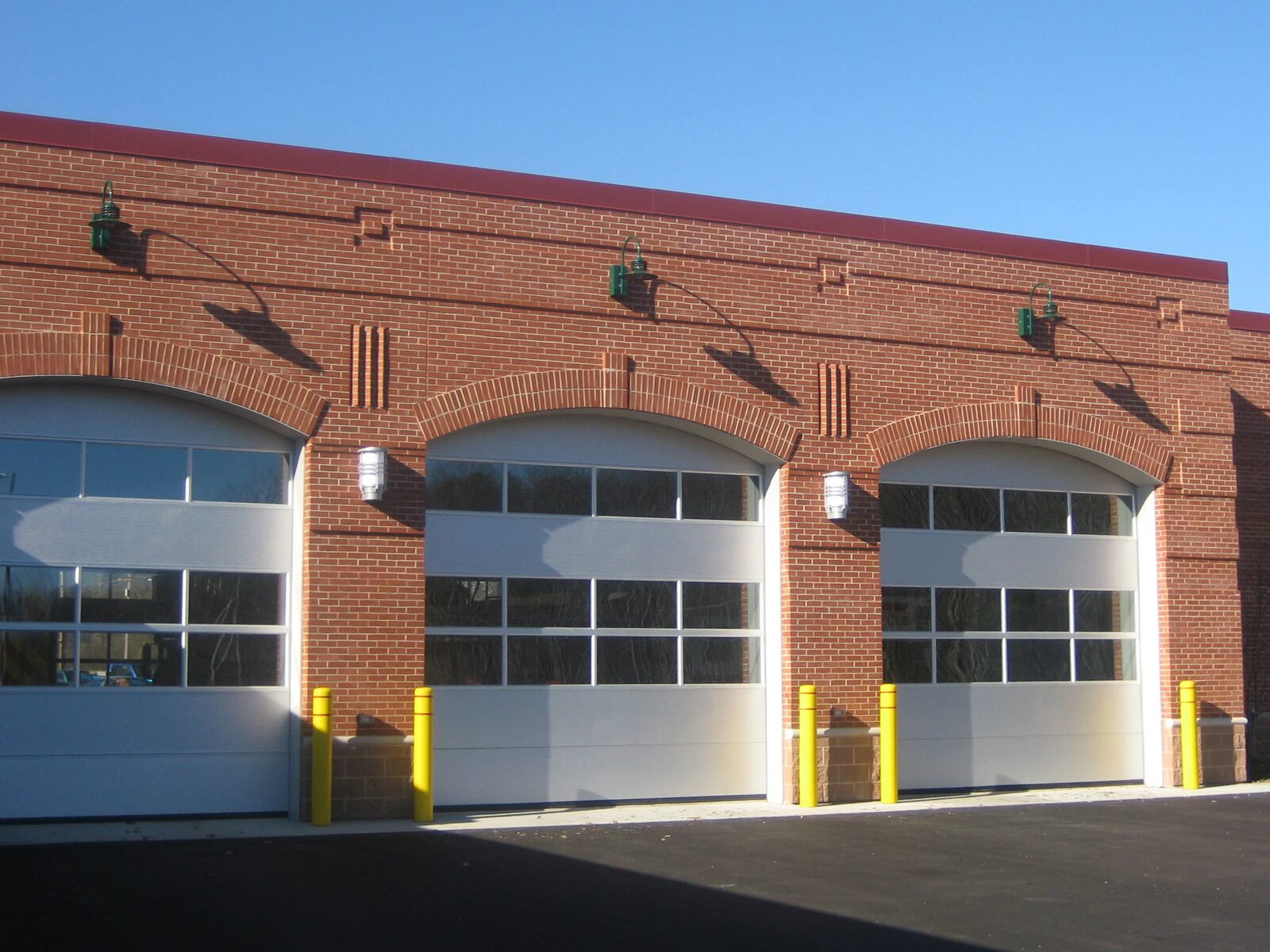 Brick apparatus bay door elevation of the Dover fire station with exterior wall pack lighting above each arched door