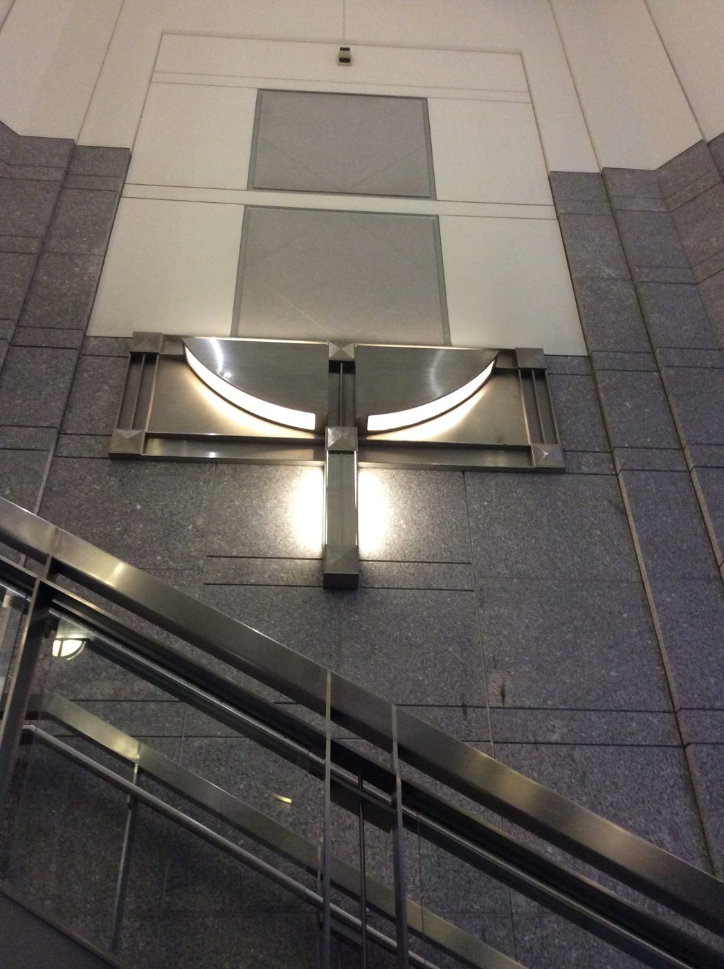 Stainless steel wall sconce above a stairway in a granite lobby at a federal courthouse