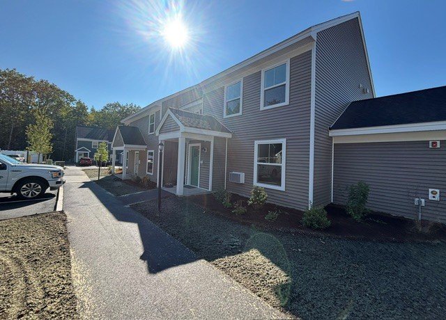 Townhouse entry walkway beside a brown and grey multi-unit building