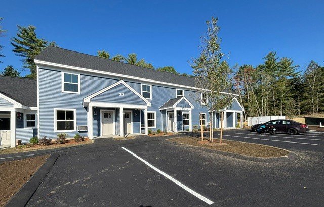 Blue and grey townhouse buildings beside a newly paved parking area