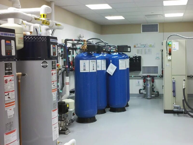Clinic mechanical and equipment room at Maplewood Dental Group in Nashua, New Hampshire, with water treatment tanks, water heater and a wall-mounted control panel