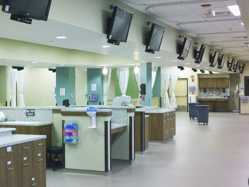 Open dental operatory bay at Maplewood Dental Group in Nashua, New Hampshire, with ceiling-mounted monitors, pendant and recessed lighting over each chair position