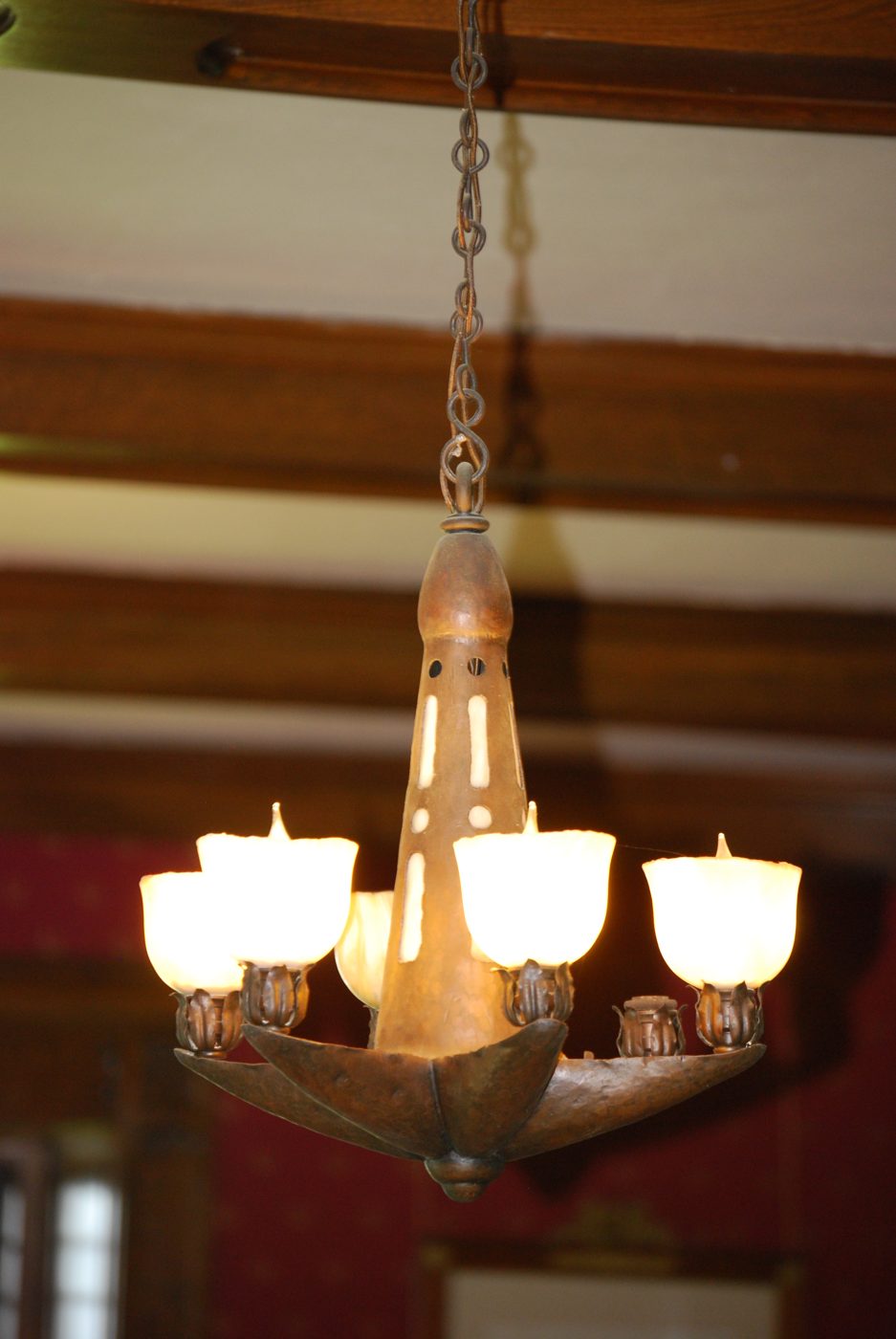 Hammered copper and mica pendant chandelier hanging from a beamed ceiling