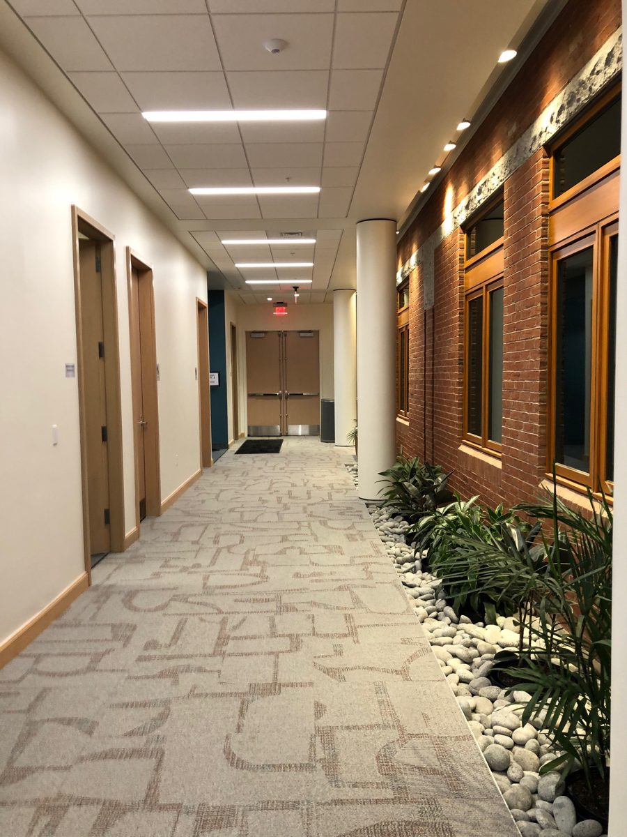 Office corridor with recessed ceiling lights and wall washers on a brick feature wall