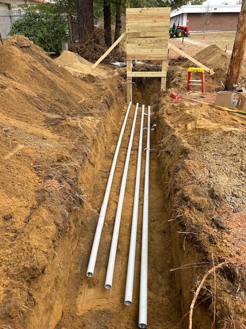 Four PVC conduits laid in an open trench for a new underground electrical service