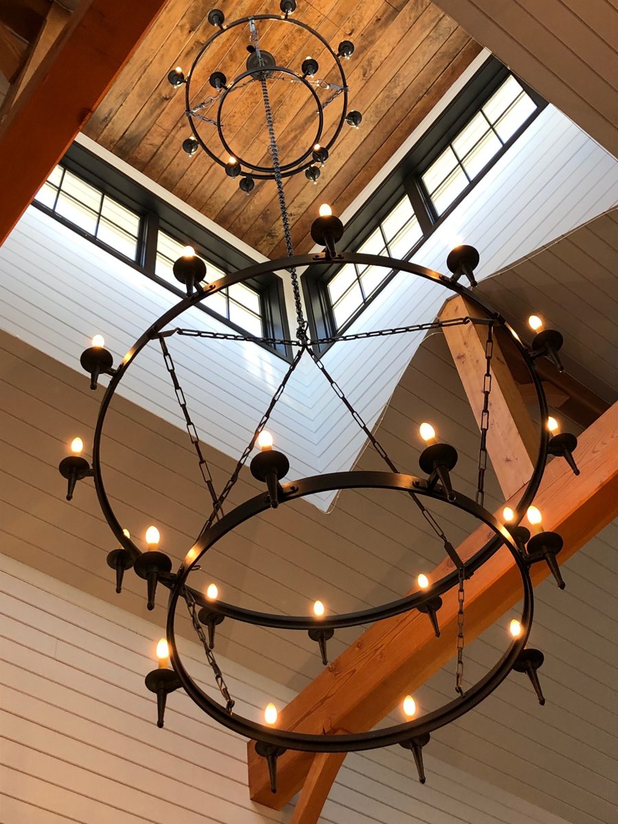 Two tier iron ring chandelier hung from a timber frame ceiling in a New Hampshire barn